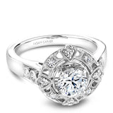 A Noam Carver white gold engagement ring with a round center stone on a detailed halo and 12 diamonds.