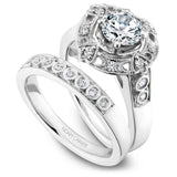 A Noam Carver white gold engagement ring with a round center stone on a detailed halo and 12 diamonds.