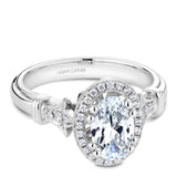 A Noam Carver white gold engagement ring with rose gold floral accents on a setting, an oval cut center stone & 30 diamonds.